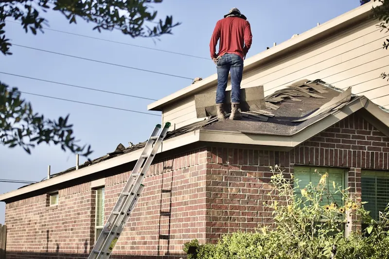 Professional roofer working on a residential roof in Foster